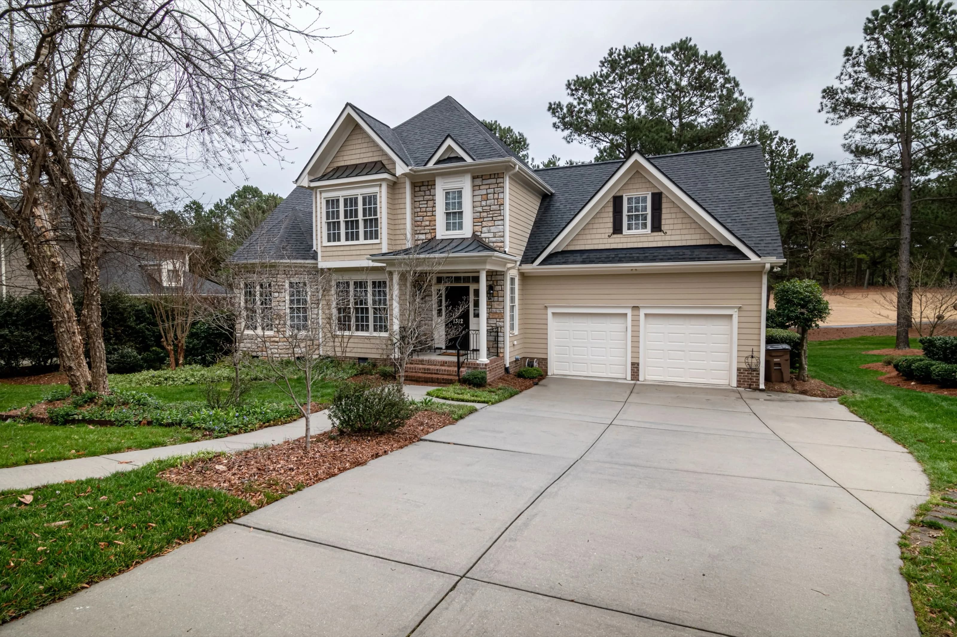 Two-story home with cedar shake siding, stone accents and white-trimmed windows